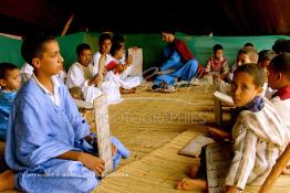 Image du Maroc Professionnelle de  Sous une tente on découvre la méthode traditionnelle de l’enseignement et l’apprentissage du saint coran prodigués aux enfants. Les jeunes récitent les sourates devant le Fkih (instituteur) qui écoute attentivement les versets ainsi récités, Samedi 18 septembre 2006, aux environ de Tan Tan dans un site désertique sur lequel la ville, a toujours accueilli la majorité des tribus et des grandes familles nomades du désert lors d'un grand Moussem, danses chants, course de chameaux et fantasia font partie des festivités. (Photo / Abdeljalil Bounhar)

 